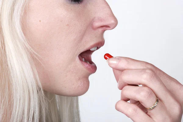 Woman holding a painkiller between finger — Stock Photo, Image