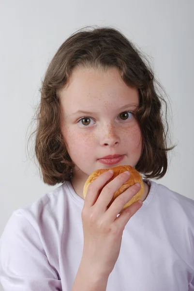 A young girl eating a bun — Stock Photo, Image