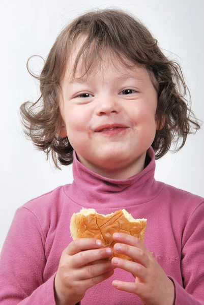Een jong meisje eet een broodje — Stockfoto