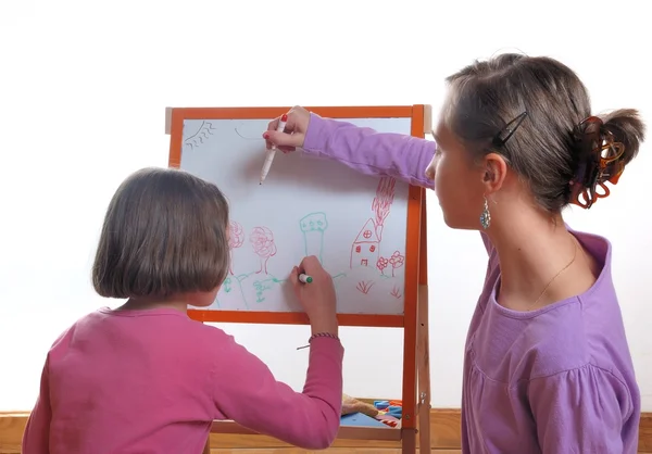 Youngs girls drawing on the white board Royalty Free Stock Photos