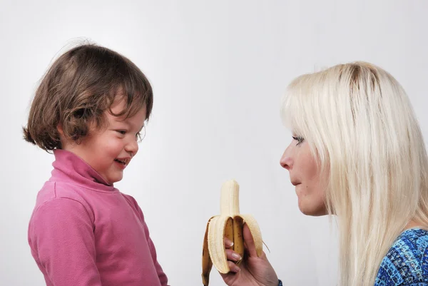 Mom giving a banana to his daughter — Stock Photo, Image