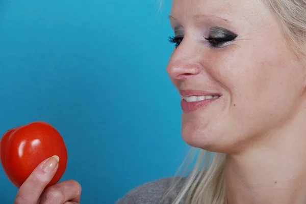 Mulher loira comendo um tomate — Fotografia de Stock