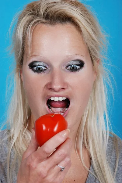 Mulher loira comendo um tomate — Fotografia de Stock