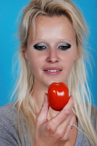Blond womanl eating a tomato — Zdjęcie stockowe
