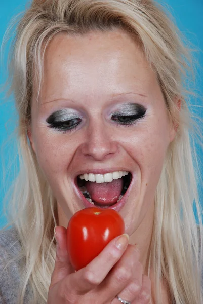 Femme blonde mangeant une tomate — Photo