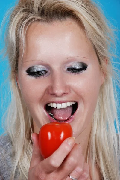 Mulher loira comendo um tomate — Fotografia de Stock