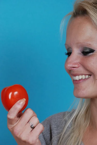 Mulher loira comendo um tomate — Fotografia de Stock