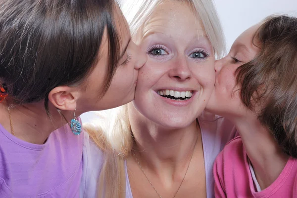 Una madre sonríe mientras recibe un beso en la mejilla de su — Foto de Stock