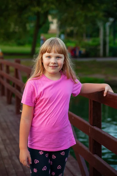 A girl in pink stands on the bridge. — Stock Photo, Image