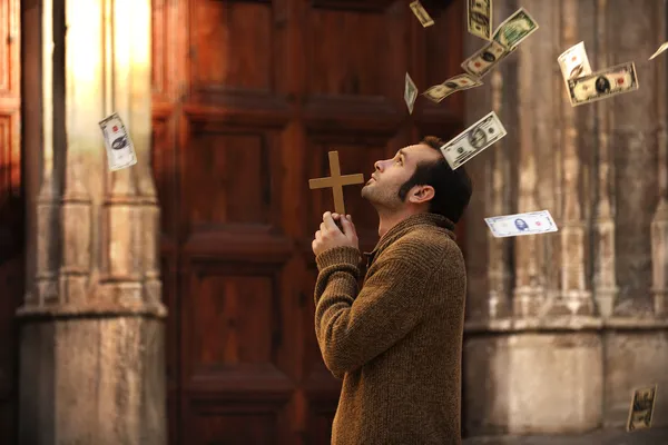 Человек молится и деньги падают с неба — стоковое фото