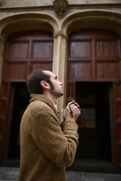 Homme priant dans l'église tenant des perles de prière — Photo