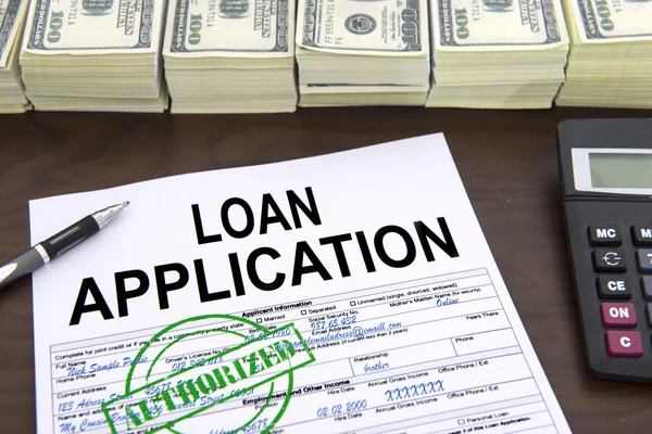 Approved loan application form and stacks of 100 dollar bills 