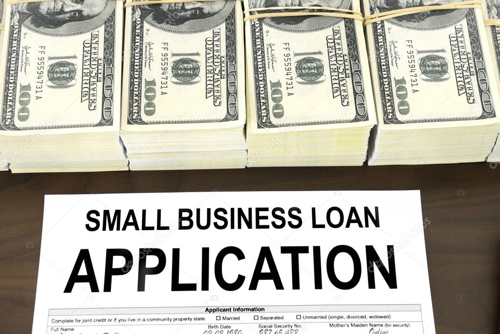 Approved small business loan application form and stacks of 100 dollar bills