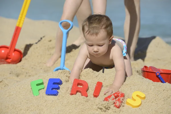 Baby op het strand met het schrijven van ferias — Stockfoto