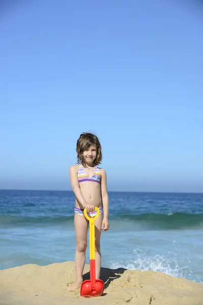 Klein meisje met schop op strand — Stockfoto