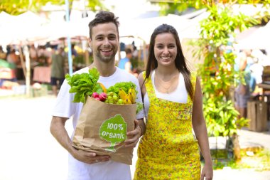 meyve ve vegetabes dolu bir alışveriş kesekâğıdı ile mutlu bir çift