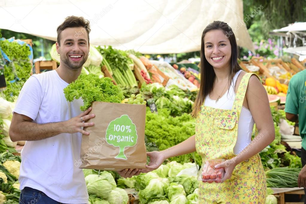 Small business owner selling organic fruits and vegetables to a woman