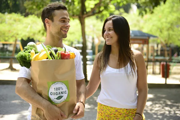 Pareja feliz llevando bolsa de comida orgánica — Foto de Stock