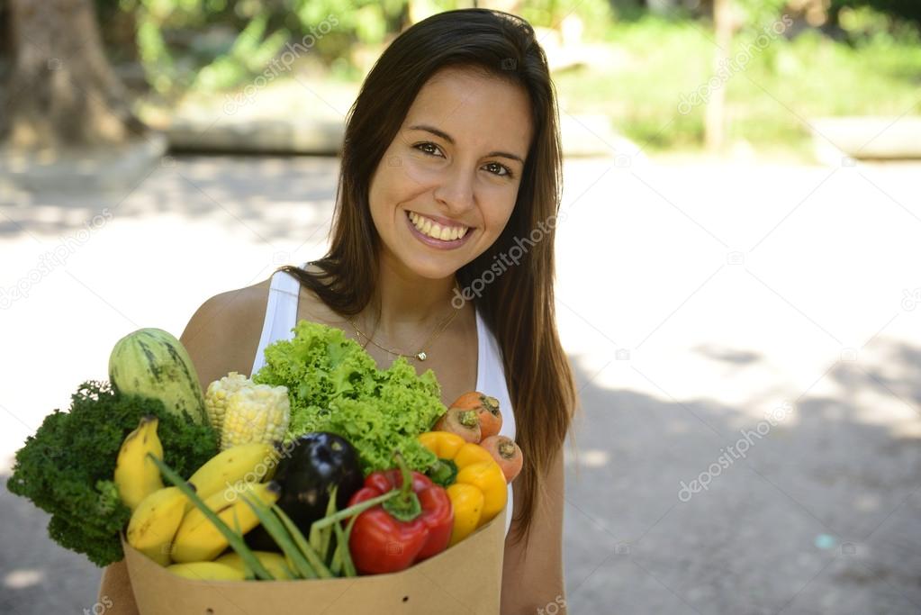 Happy woman carrying bag of organic food.