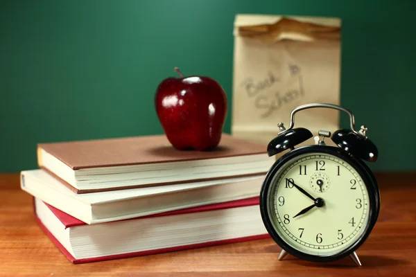 Lunch, apple, boeken en klok op Bureau op school — Stockfoto