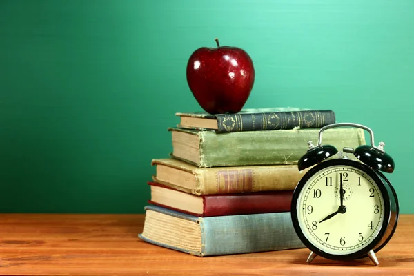 Σχολικά βιβλία, μήλο και ρολόι στην επιφάνεια εργασίας στο σχολείο — Φωτογραφία Αρχείου