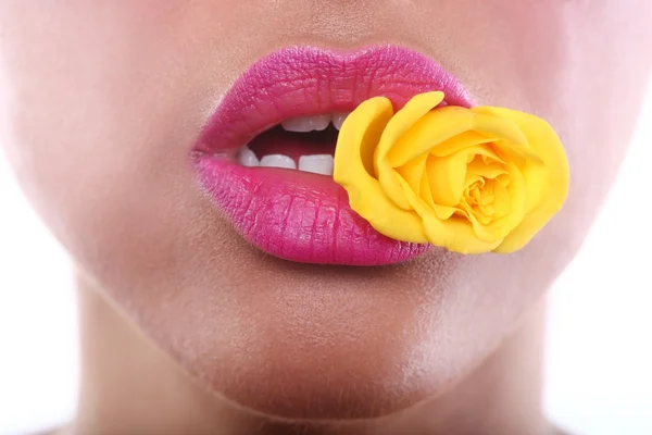 Žena s smyslné rty drží květina v ústech — Stock fotografie