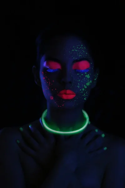 Mujer brillante usando cosméticos UV bajo luz negra — Foto de Stock