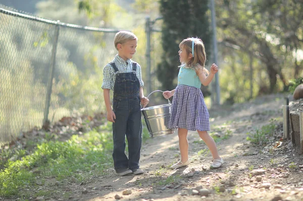 Niños trabajando en la granja con un cubo —  Fotos de Stock