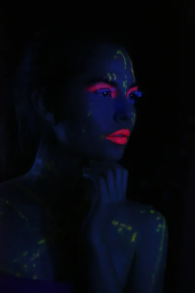 Mujer brillante usando cosméticos UV bajo luz negra — Foto de Stock