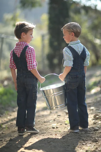 Niños trabajando en la granja con un cubo —  Fotos de Stock