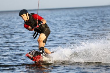 Wakeboarder surfing across a river clipart