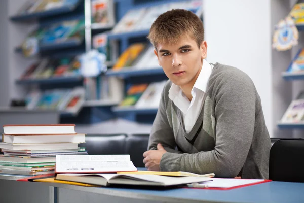 Bonito estudante do sexo masculino em uma biblioteca — Fotografia de Stock