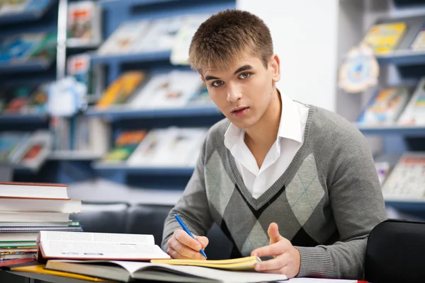 Bonito estudante do sexo masculino em uma biblioteca — Fotografia de Stock