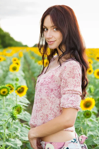 Krásná dáma chůze ve slunečnicovém poli — Stock fotografie