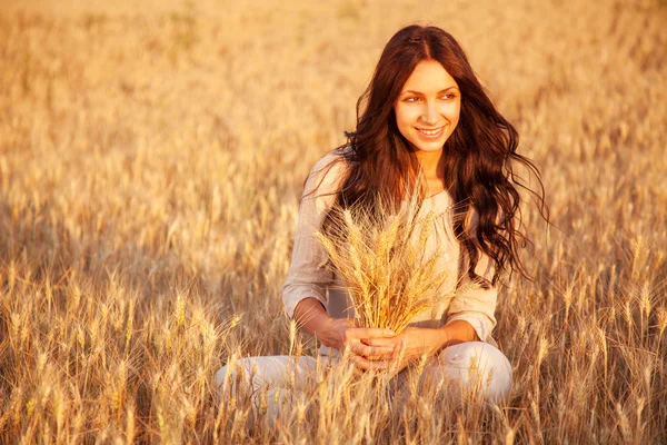Linda senhora morena no campo de trigo ao pôr do sol — Fotografia de Stock