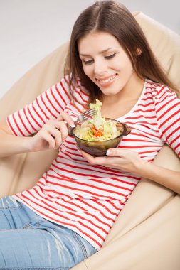 Güzel genç bir kadın salata yiyor.