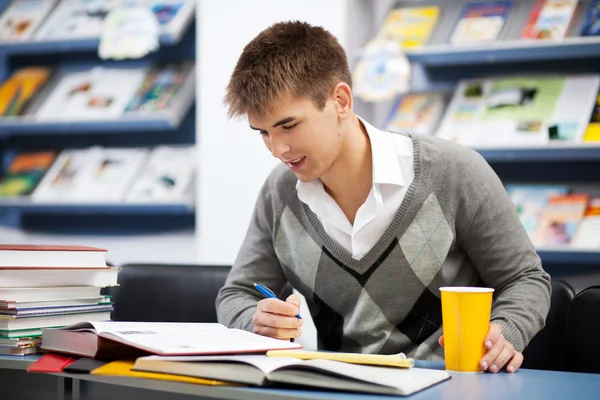 Bonito estudante do sexo masculino em uma biblioteca universitária — Fotografia de Stock