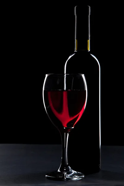 Copo de vinho e garrafa no fundo preto — Fotografia de Stock