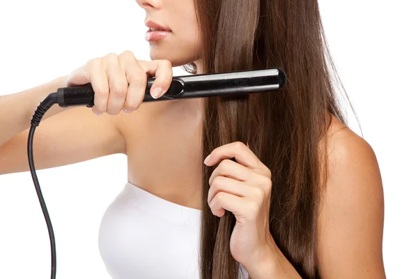 Jonge vrouw met een hair straightener — Stockfoto