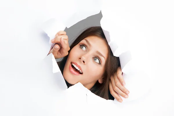 Jeune femme percer à travers une feuille de papier — Photo