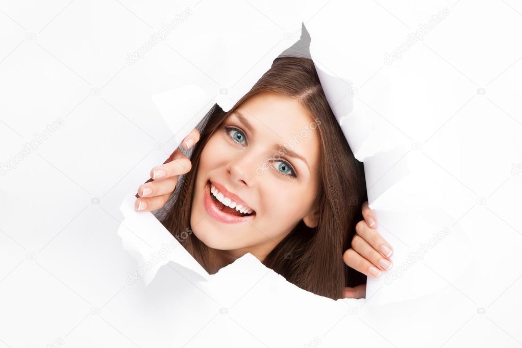 Young woman breaking through a paper sheet
