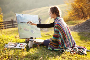 Genç ressam sonbahar manzarası çiziyor.