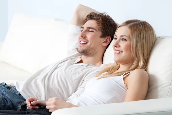 Jeune beau couple sur un canapé à la maison — Photo