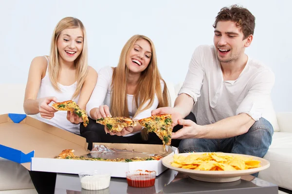 群年轻人在家吃披萨 免版税图库图片