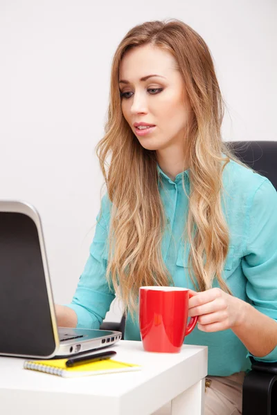 Jonge blonde vrouw die met een laptop werkt — Stockfoto