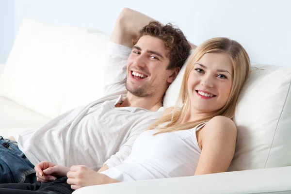 Jeune beau couple sur un canapé à la maison — Photo