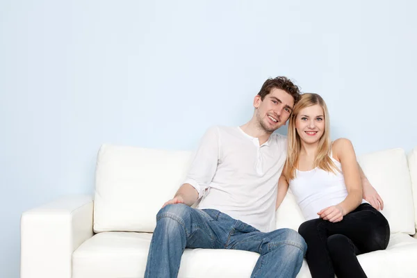 Jovem casal bonito em um sofá em casa — Fotografia de Stock