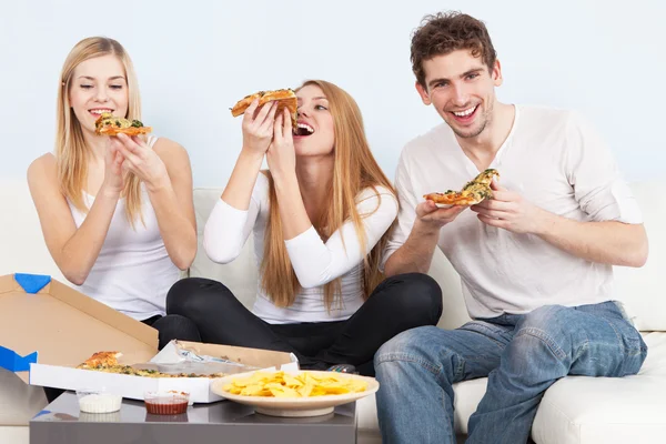 Groupe de jeunes mangeant des pizzas à la maison — Photo