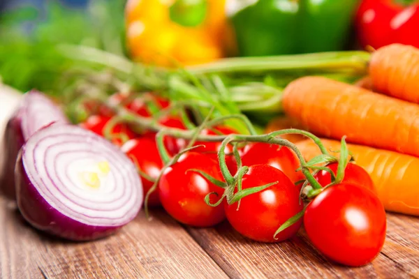 Carrot, tomato and paprika on a wooden table — Stock Photo, Image