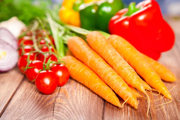 Carrot, tomato and paprika on a wooden table — Stock Photo, Image